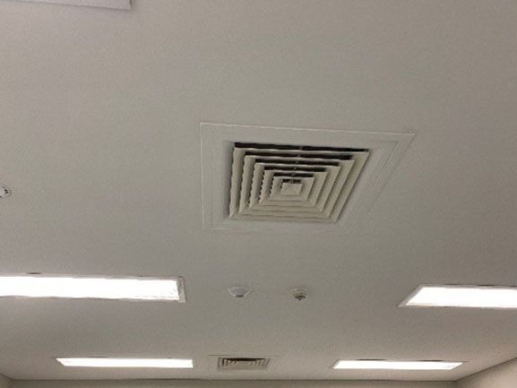 Ceiling with a square air vent and rectangular lights.