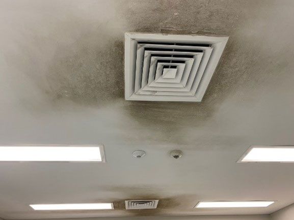 Ceiling with a dark stain around the air vent, possibly mold or water damage.