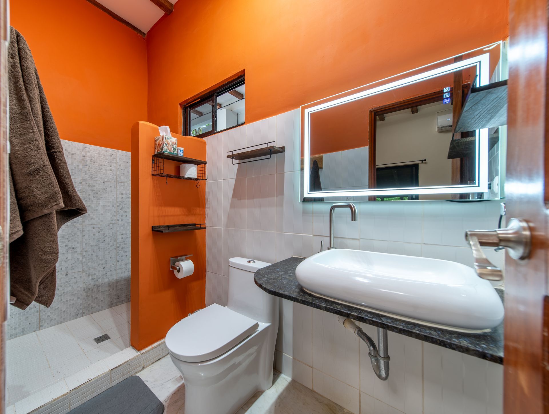 A bathroom with a toilet , sink and mirror.