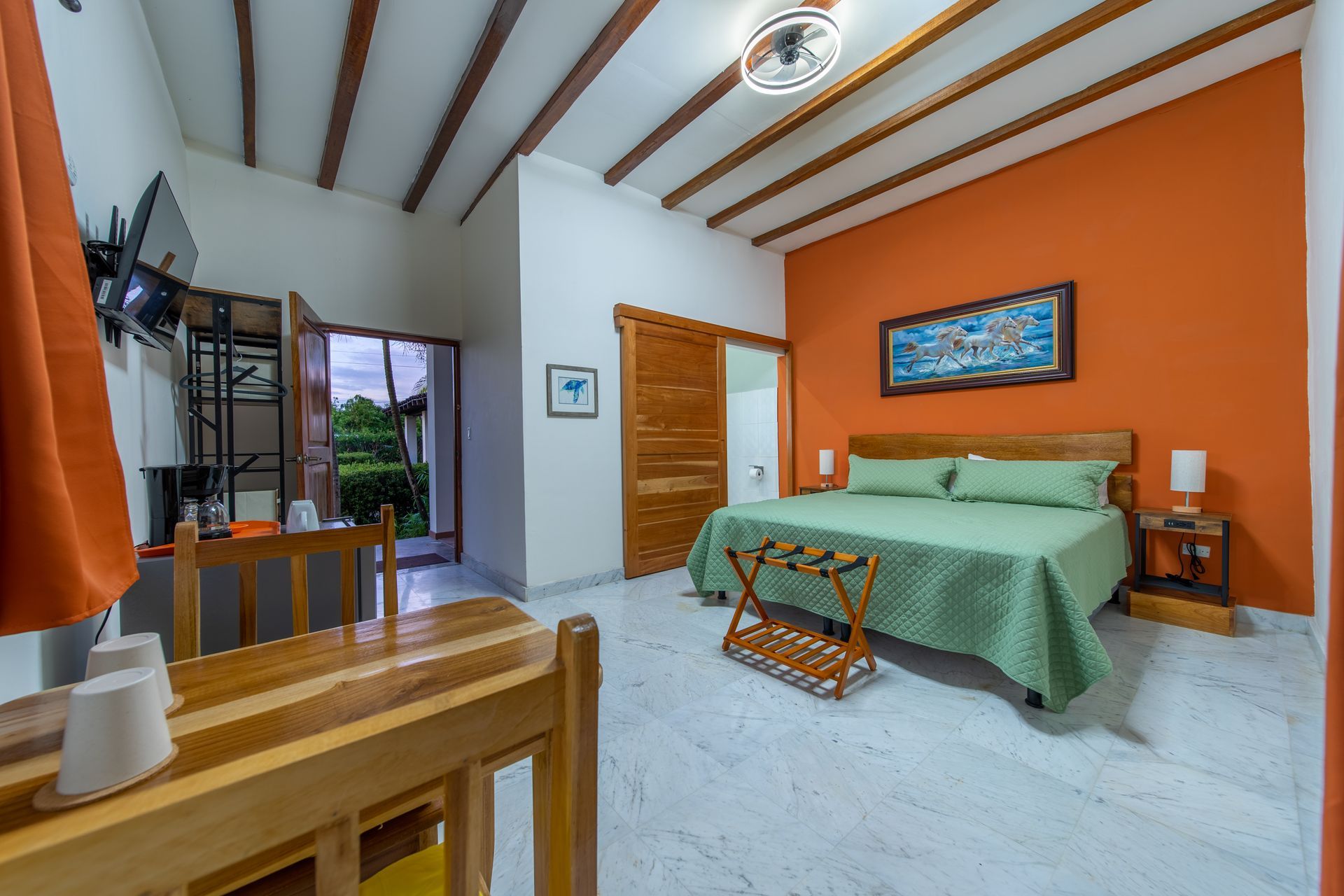 A hotel room with a bed , table , chairs and television.