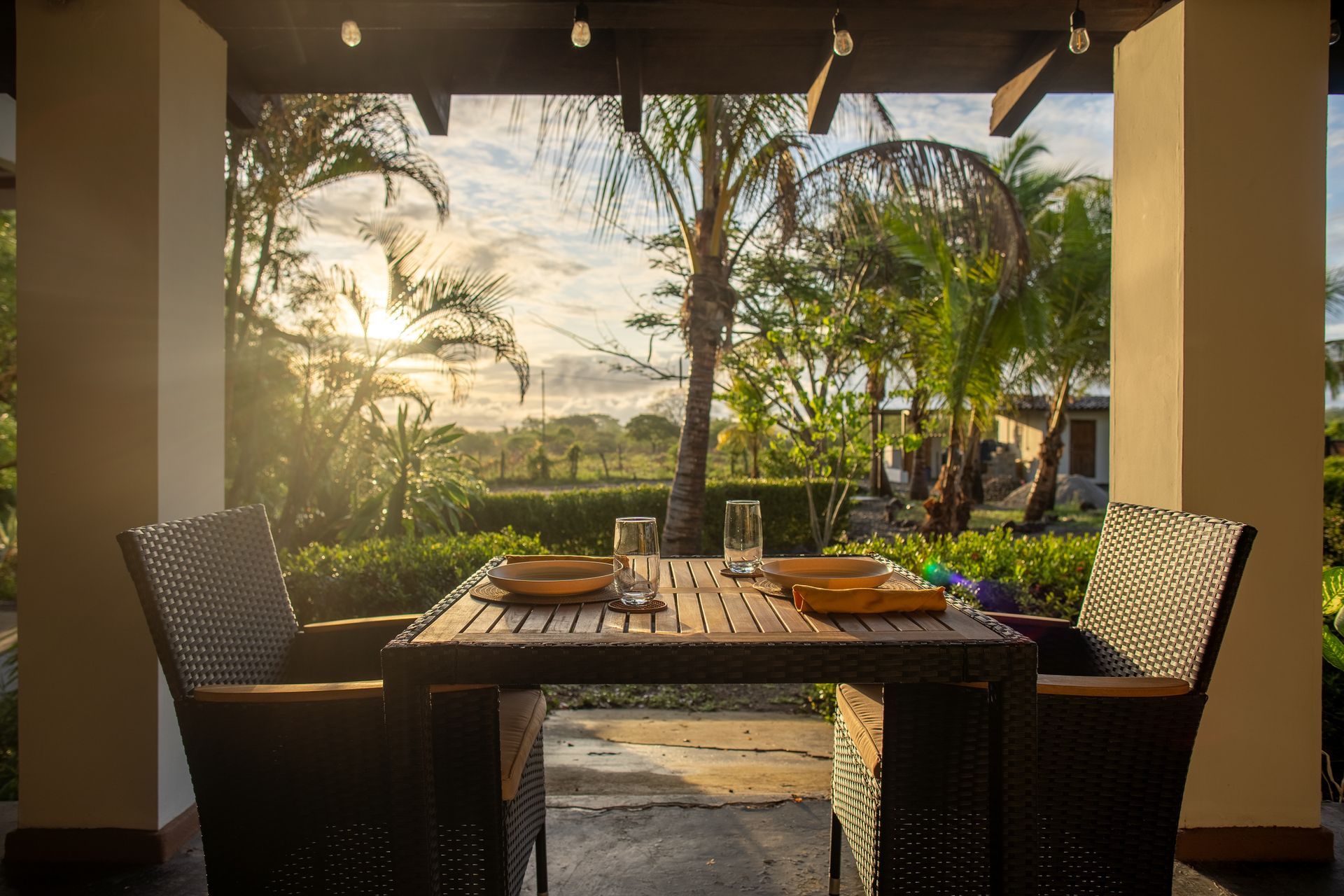 A patio with a table and chairs and a view of the sunset.
