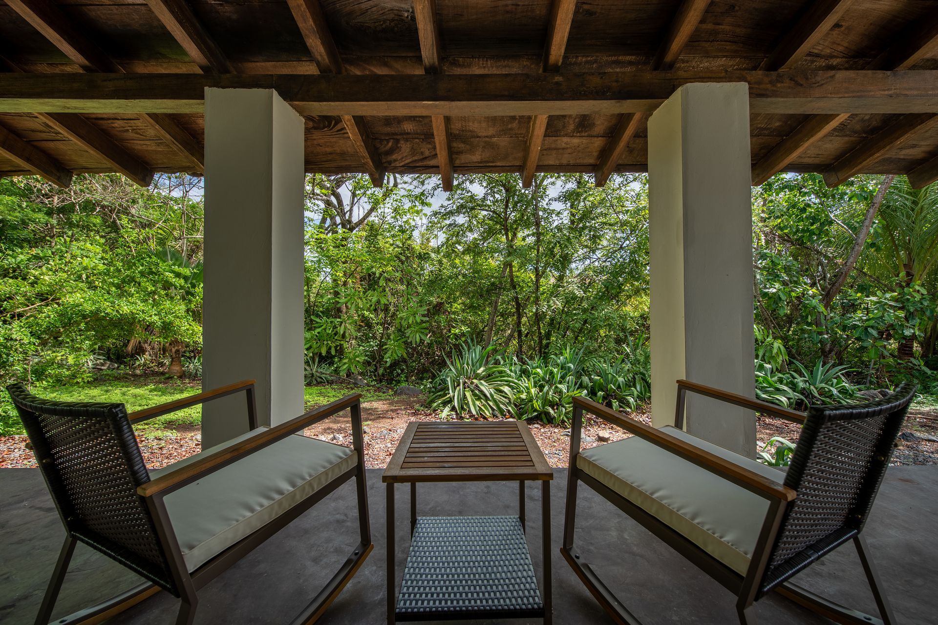 There are two chairs and a table on the porch.