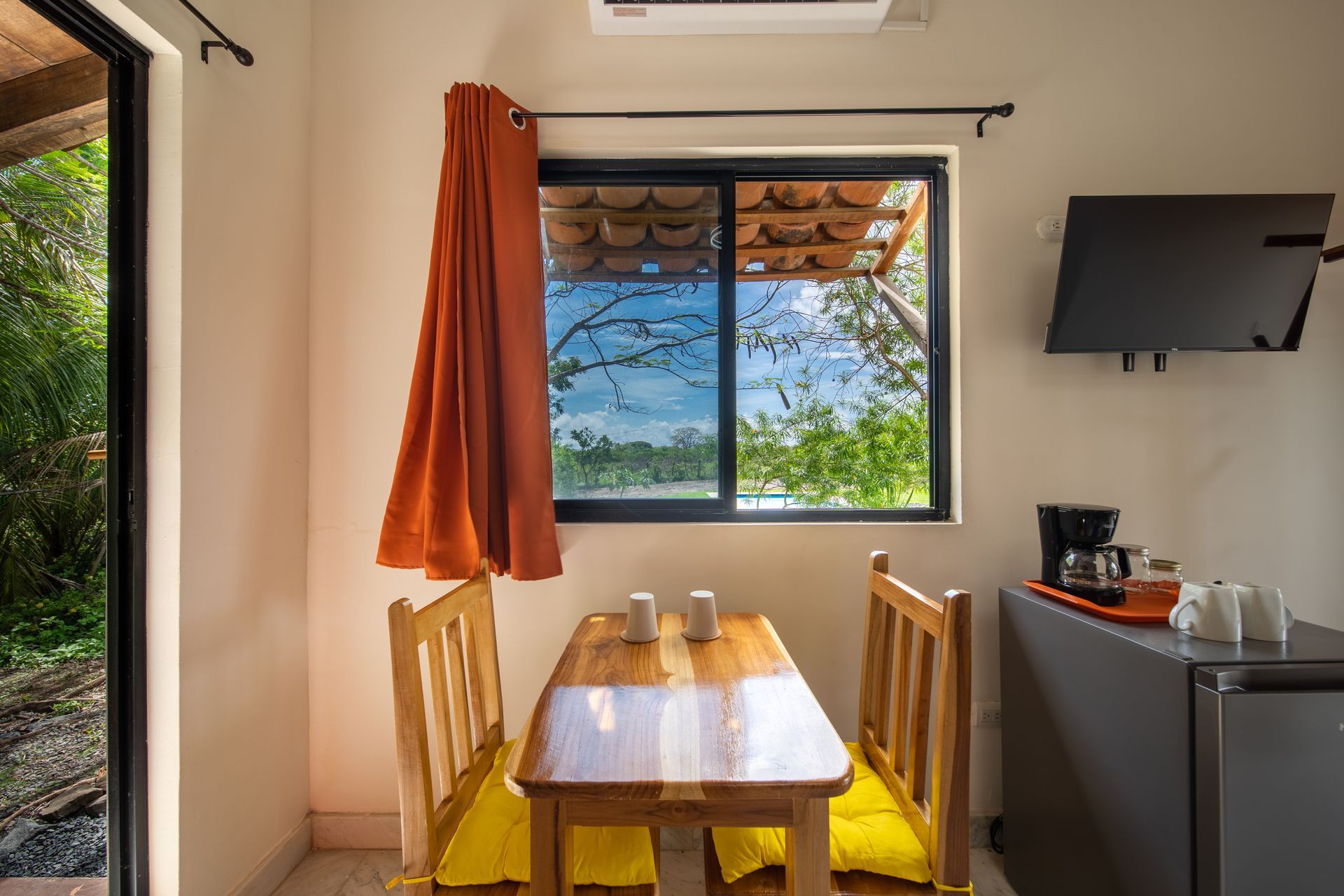 There is a table and chairs in the room with a window.