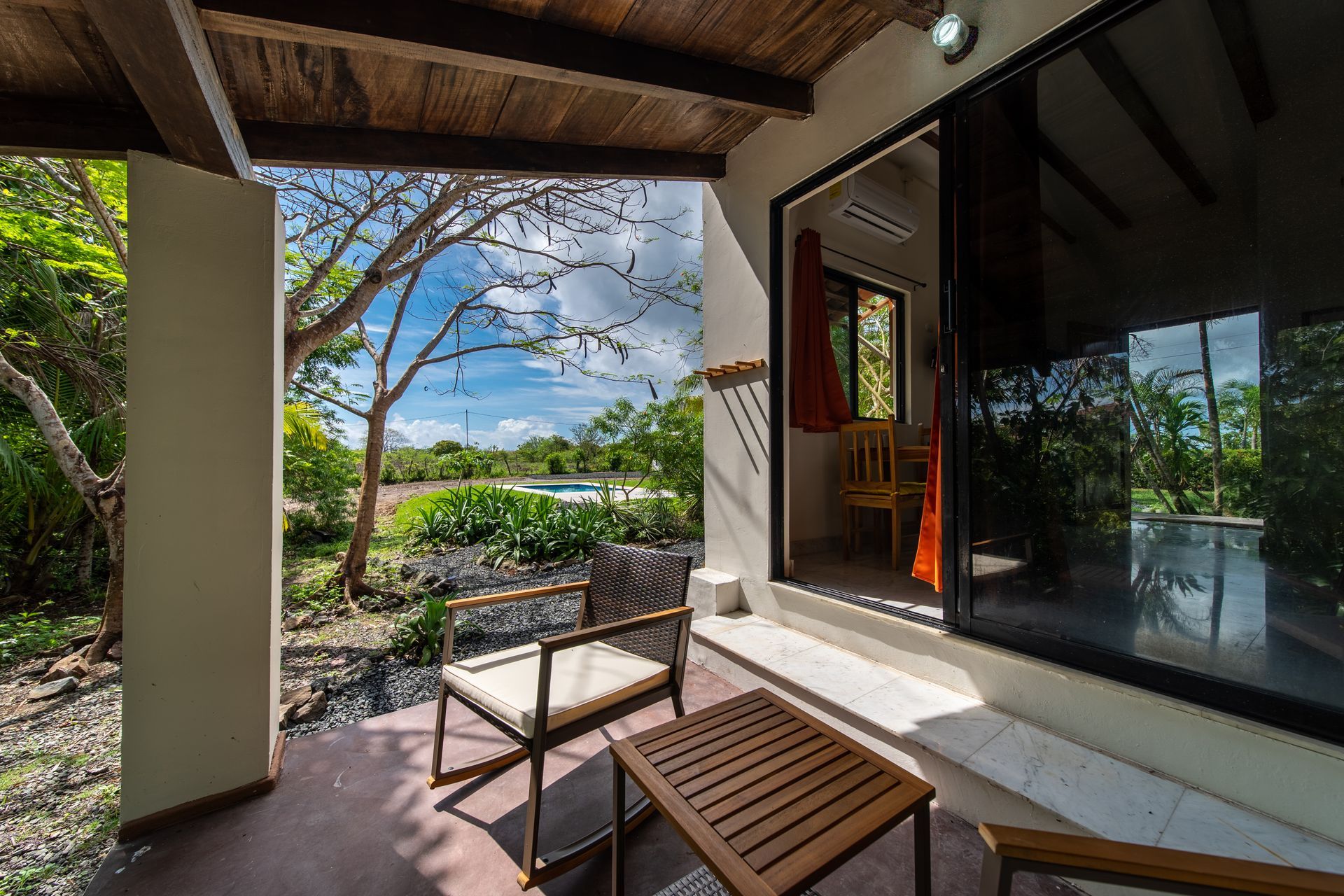A patio with chairs and a table in front of a window.