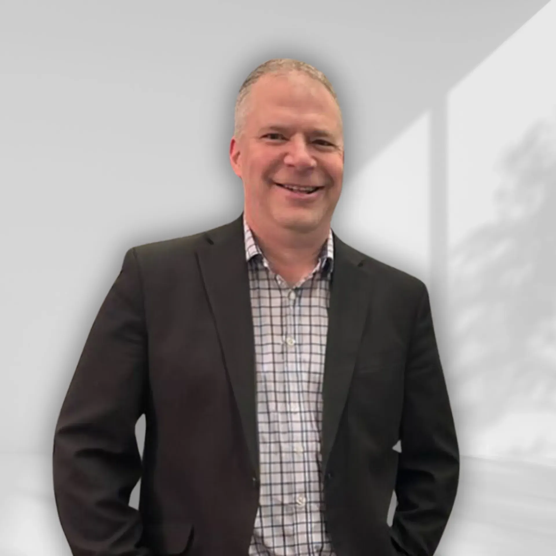 A man in a suit and tie is standing next to a wall.
