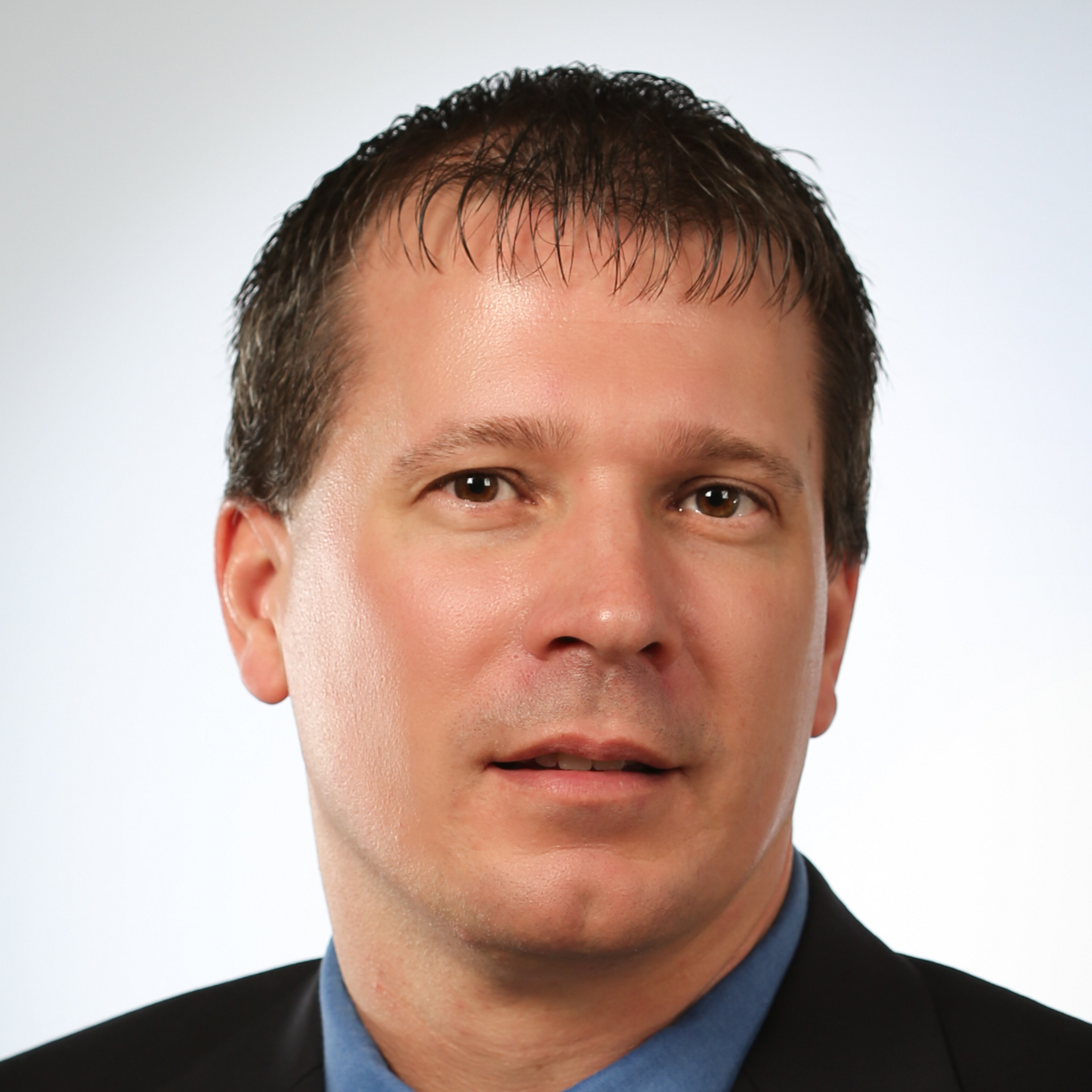 A man in a suit and blue shirt looks at the camera