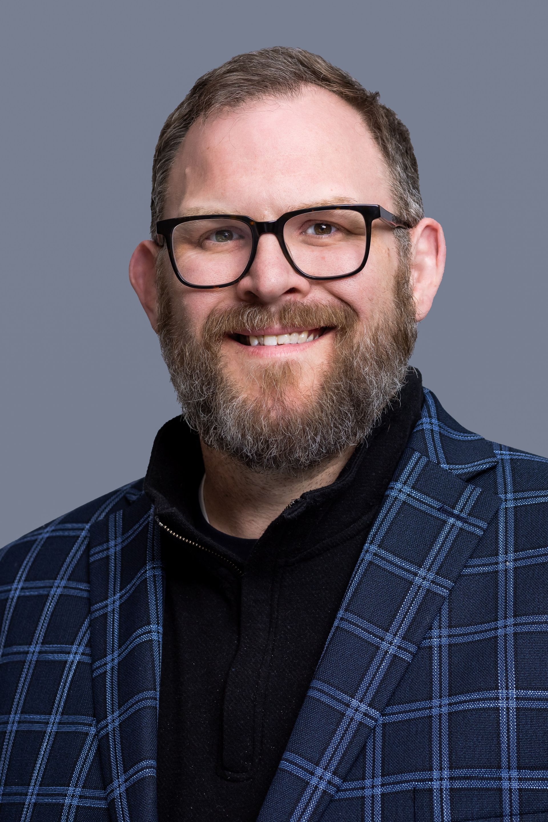 A man in a suit and blue shirt looks at the camera