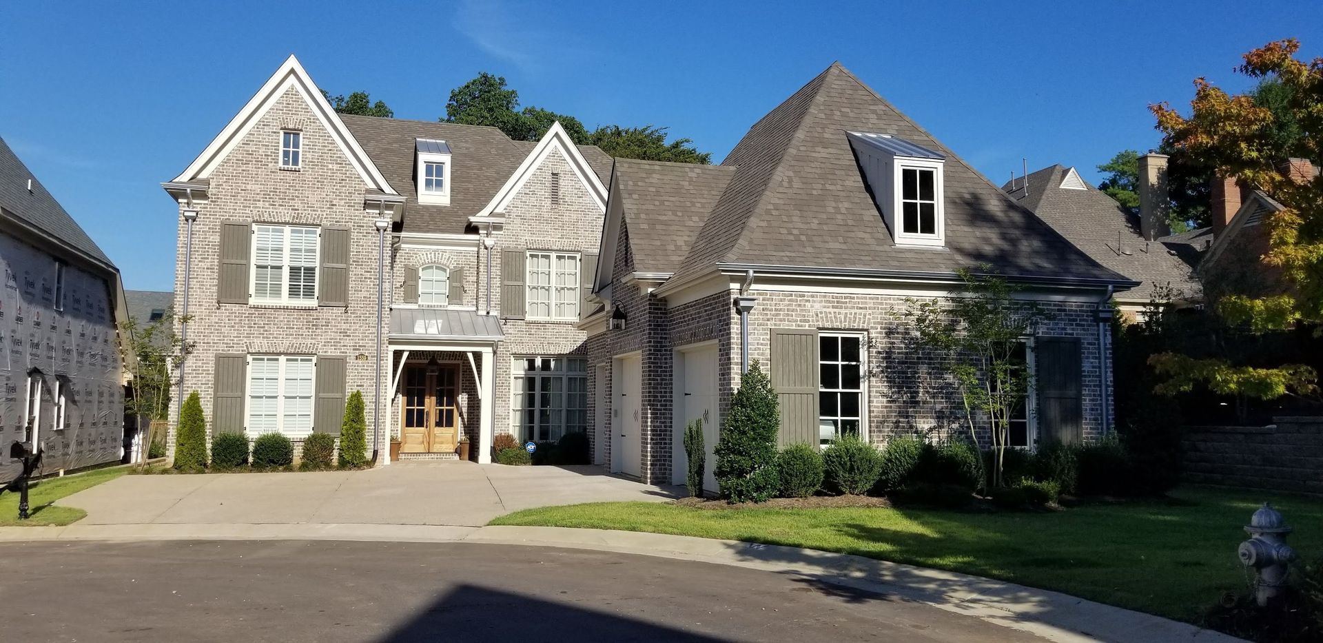 Stone house with gray shutters and a blue sky.
