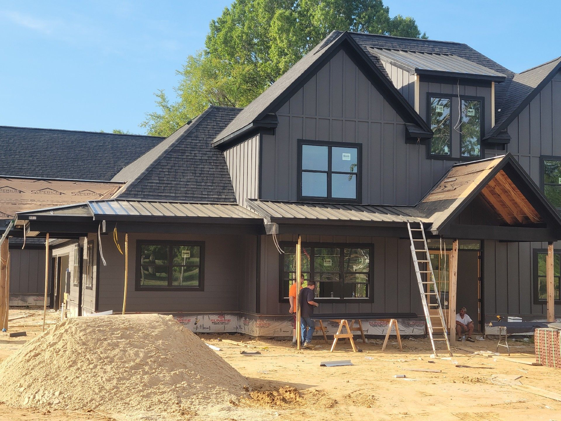 New house under construction, featuring white siding and a stone section on a cloudy day.