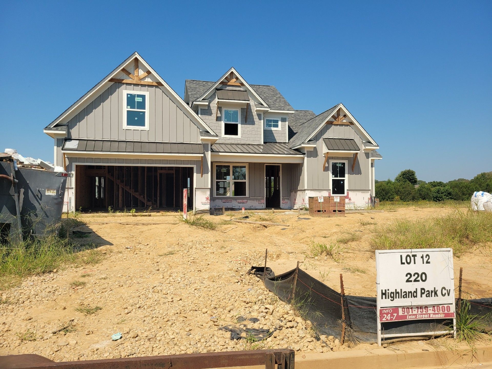 New house under construction on Lot 12 in Highland Park Co. Gray siding, garage, windows, and a sign.