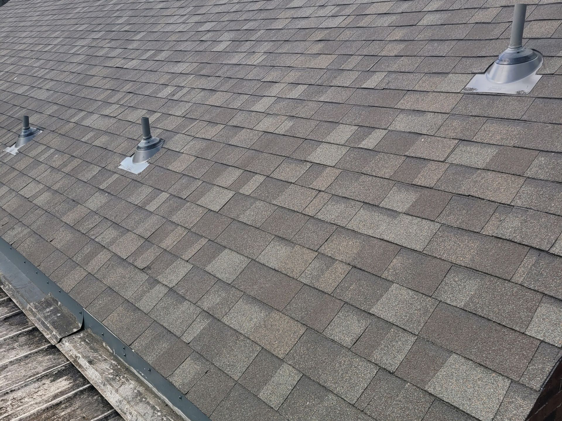 A gray shingle roof with several vents.