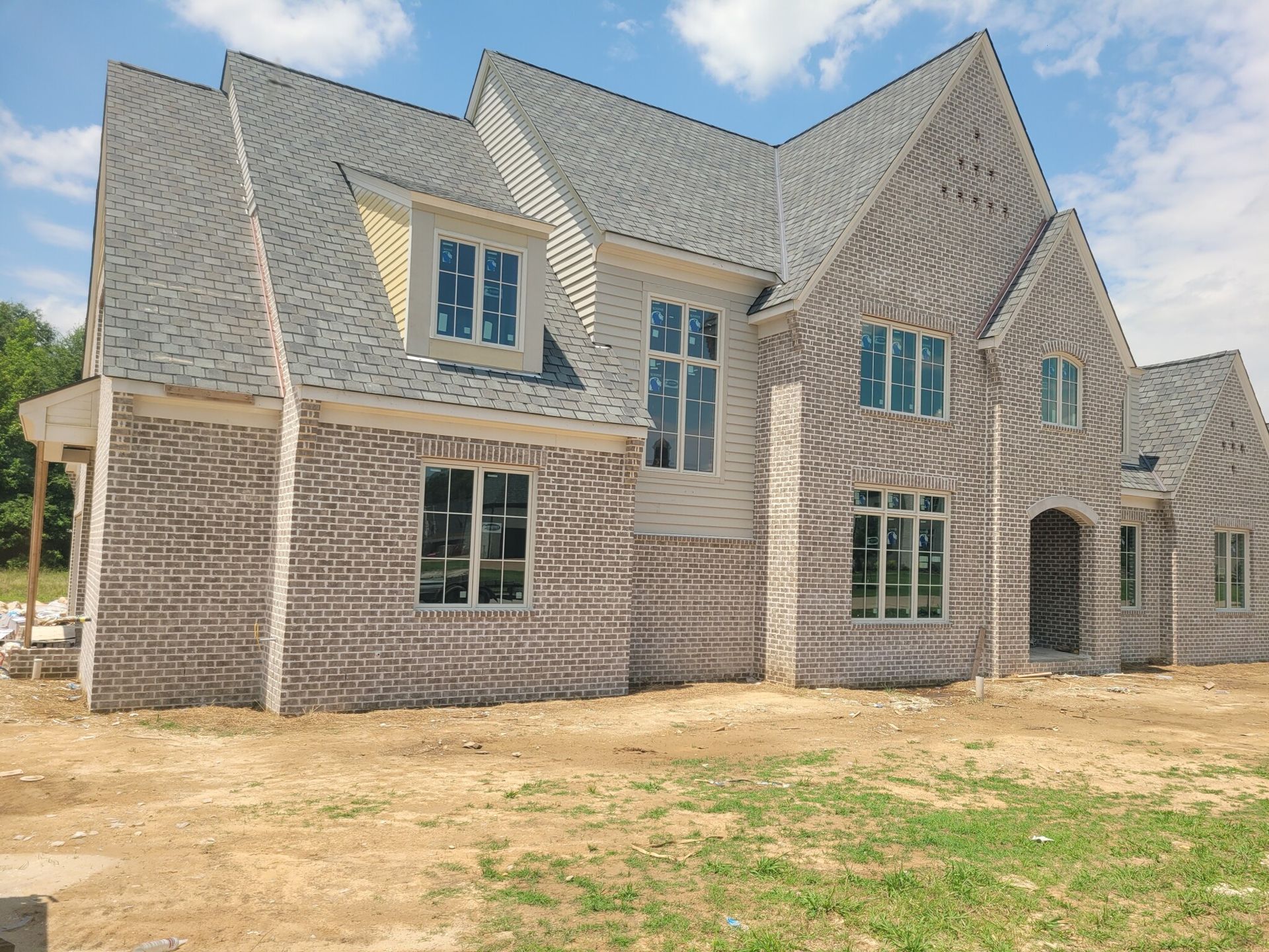 New house under construction with brick facade and gray roof.