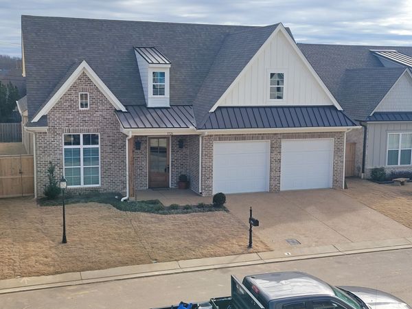 Two-car brick garage with white doors on a concrete driveway under a cloudy sky.