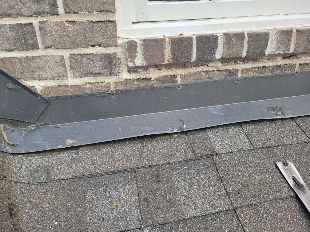 Brick chimney on a tiled roof against a blue sky.