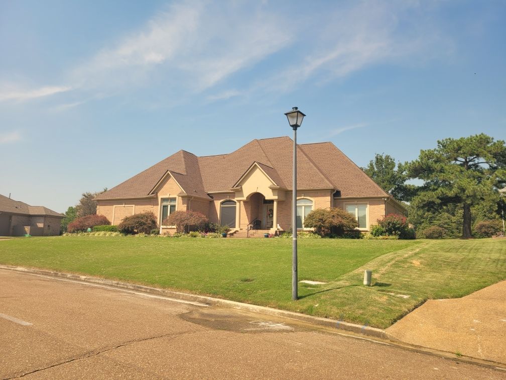 Tan metal roof next to a brown shingle roof, outdoors.