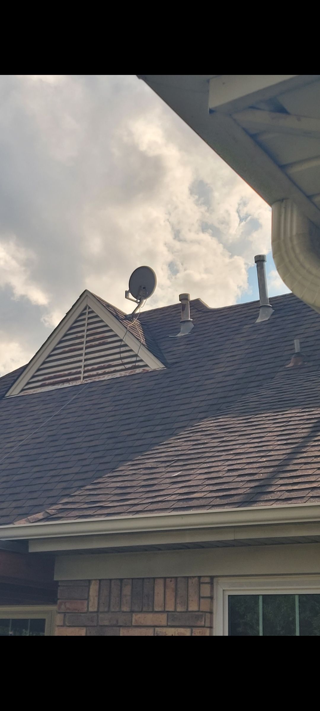House with white columns, shutters, and a gray roof. Green lawn and sidewalk in front.