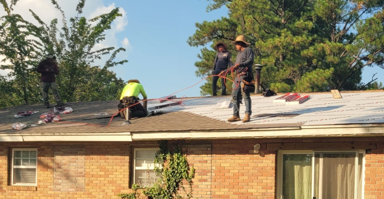 Gray metal roofing on a house with a grassy backyard and a gravel-covered roof section.