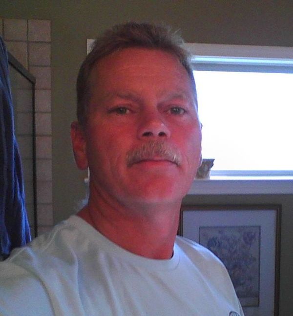 Two-car brick garage with white doors on a concrete driveway under a cloudy sky.