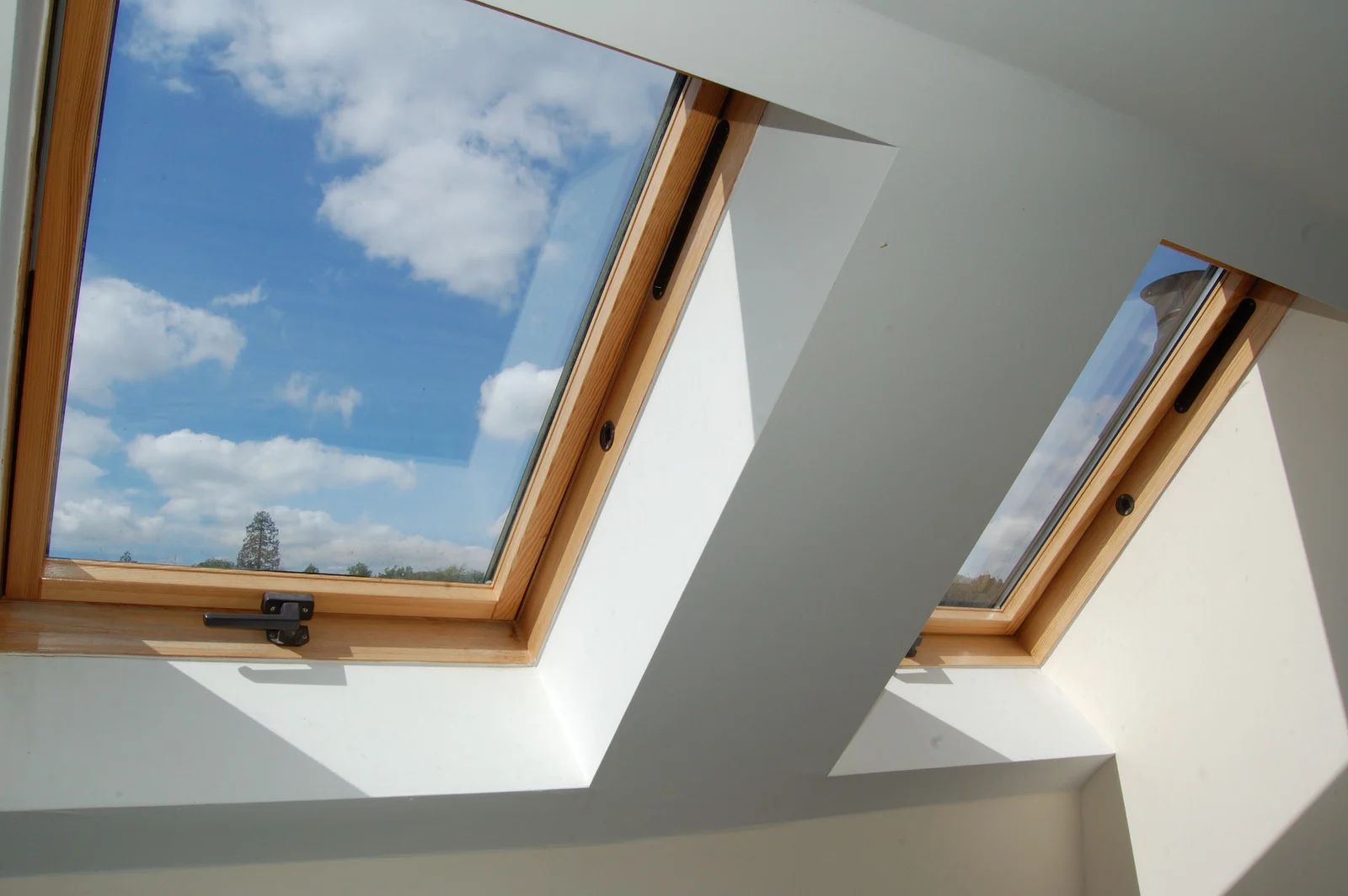 Two skylight windows in white ceiling, blue sky with clouds visible.