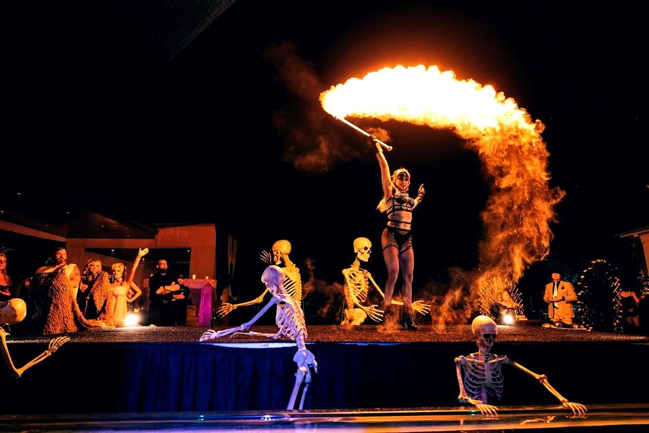 A woman is performing a fire show with skeletons on stage.