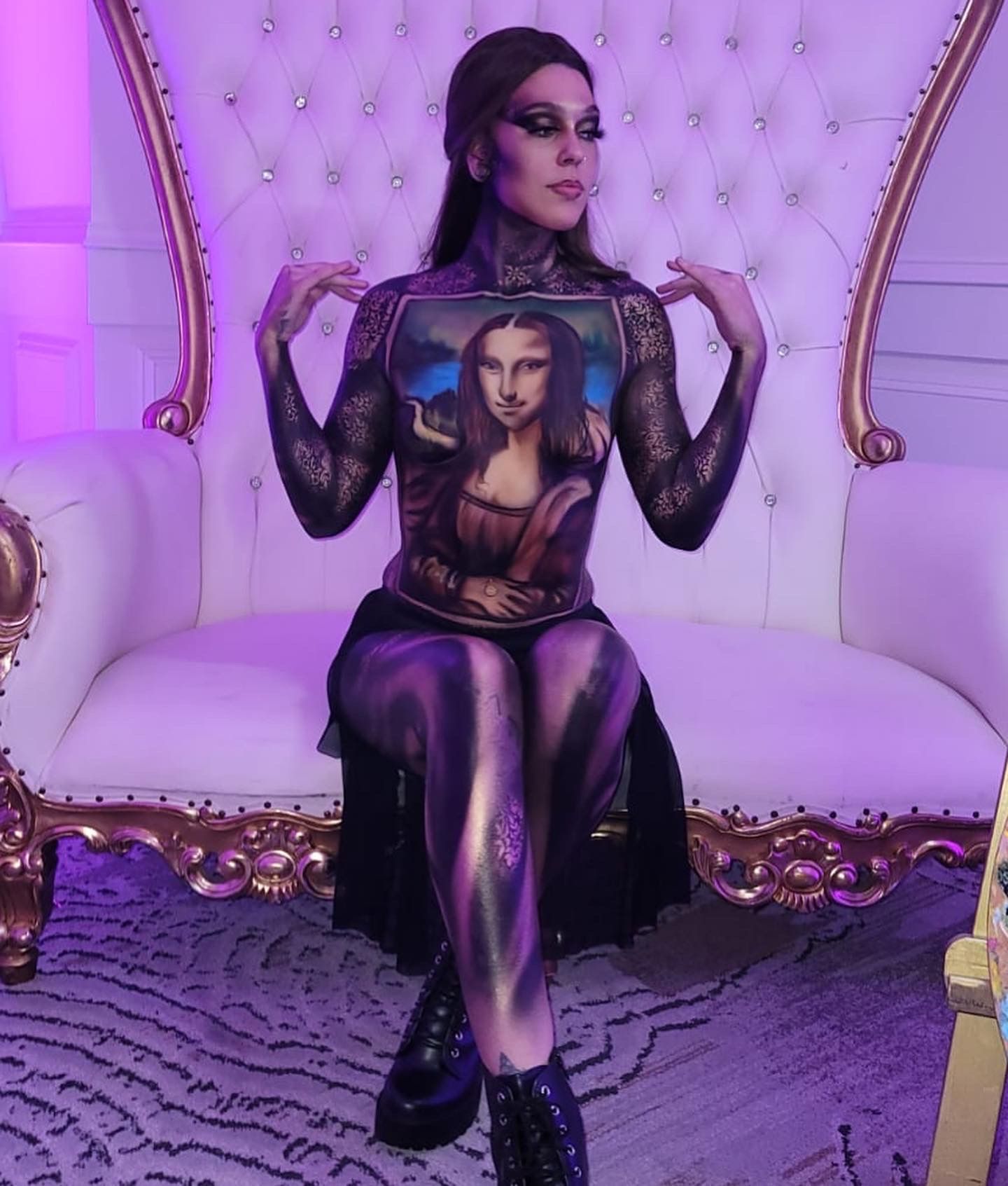 A woman is sitting in a chair with a painting of mona lisa on her chest.