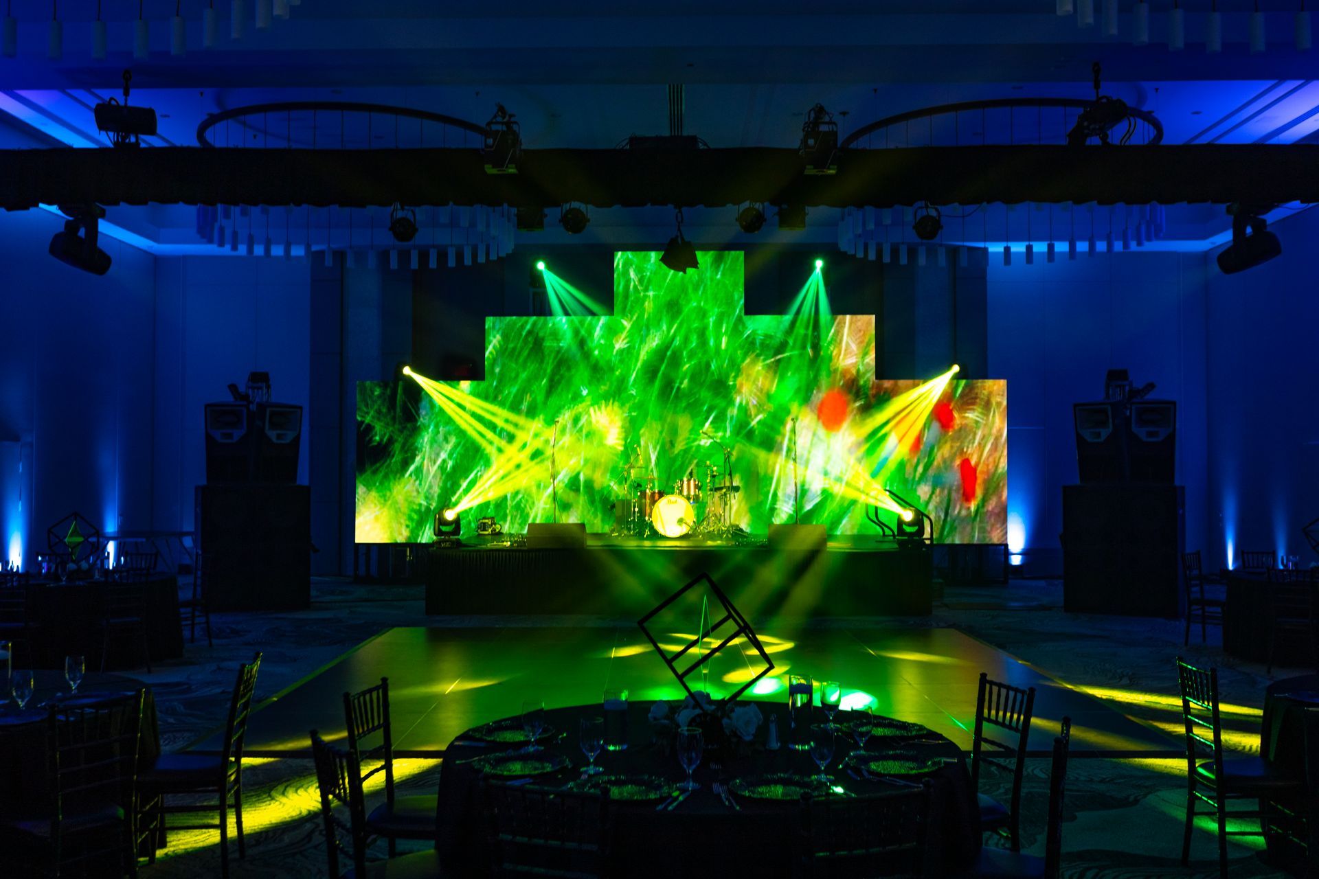 tables and chairs in front of a stage with green lights