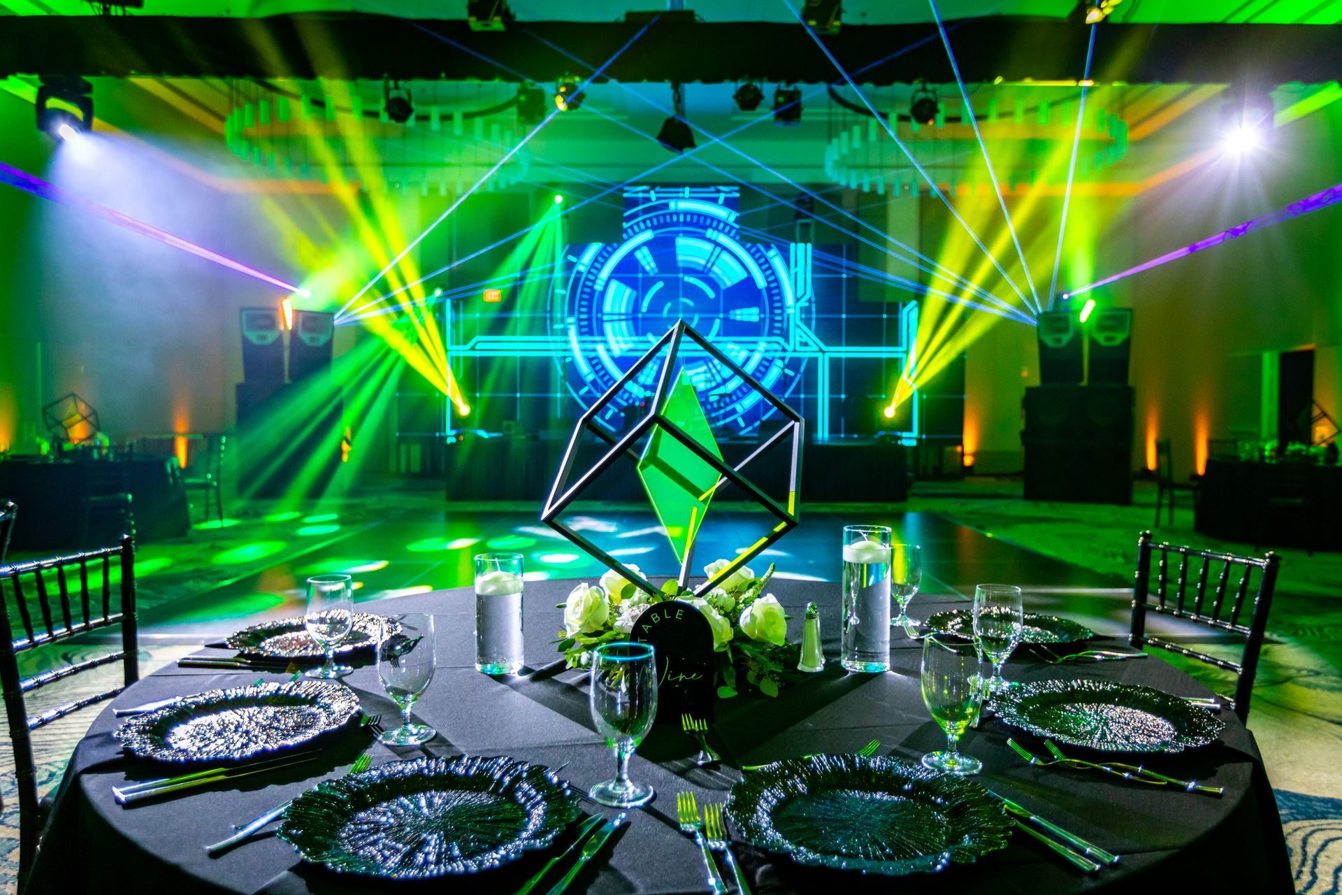 a table set for a party with green lights behind it .