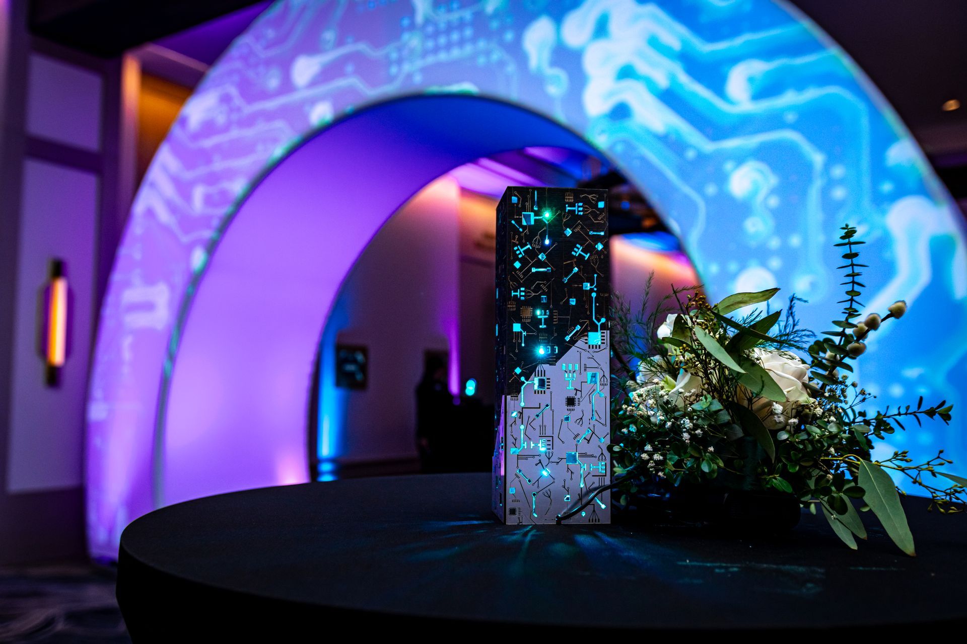 A table with flowers in front of a blue and purple archway.