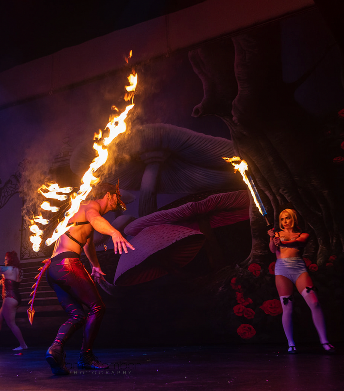 A man and a woman are performing a fire show on a stage.