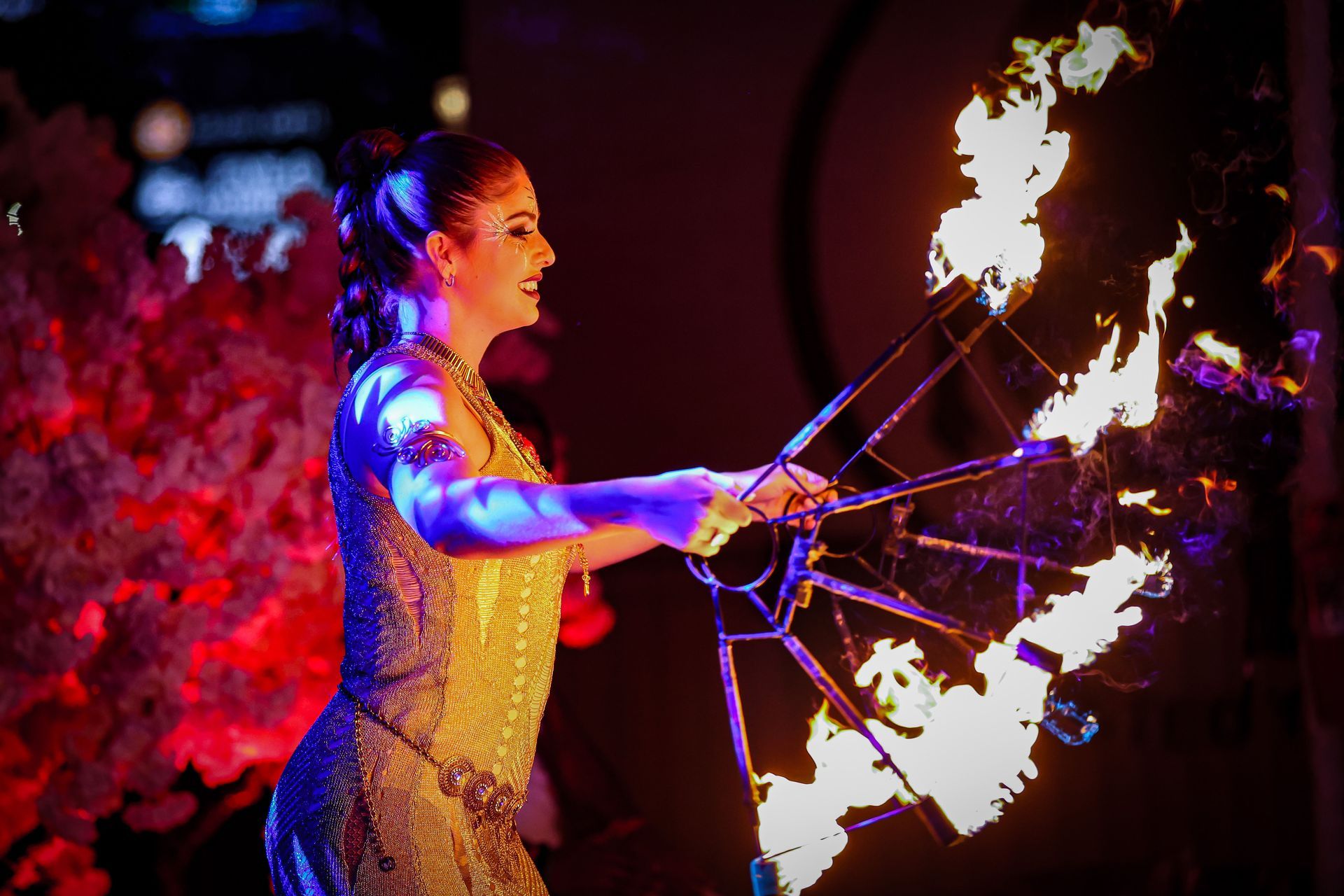 a woman in a gold dress is holding a fan of fire