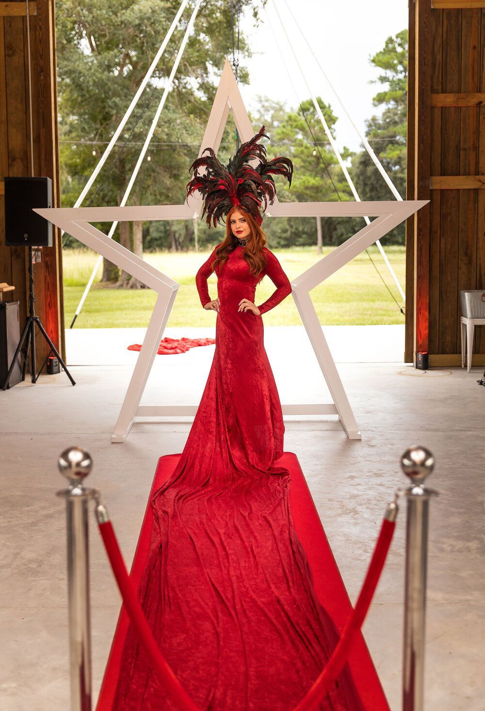 A woman in a red dress is standing on a red carpet in front of a star.