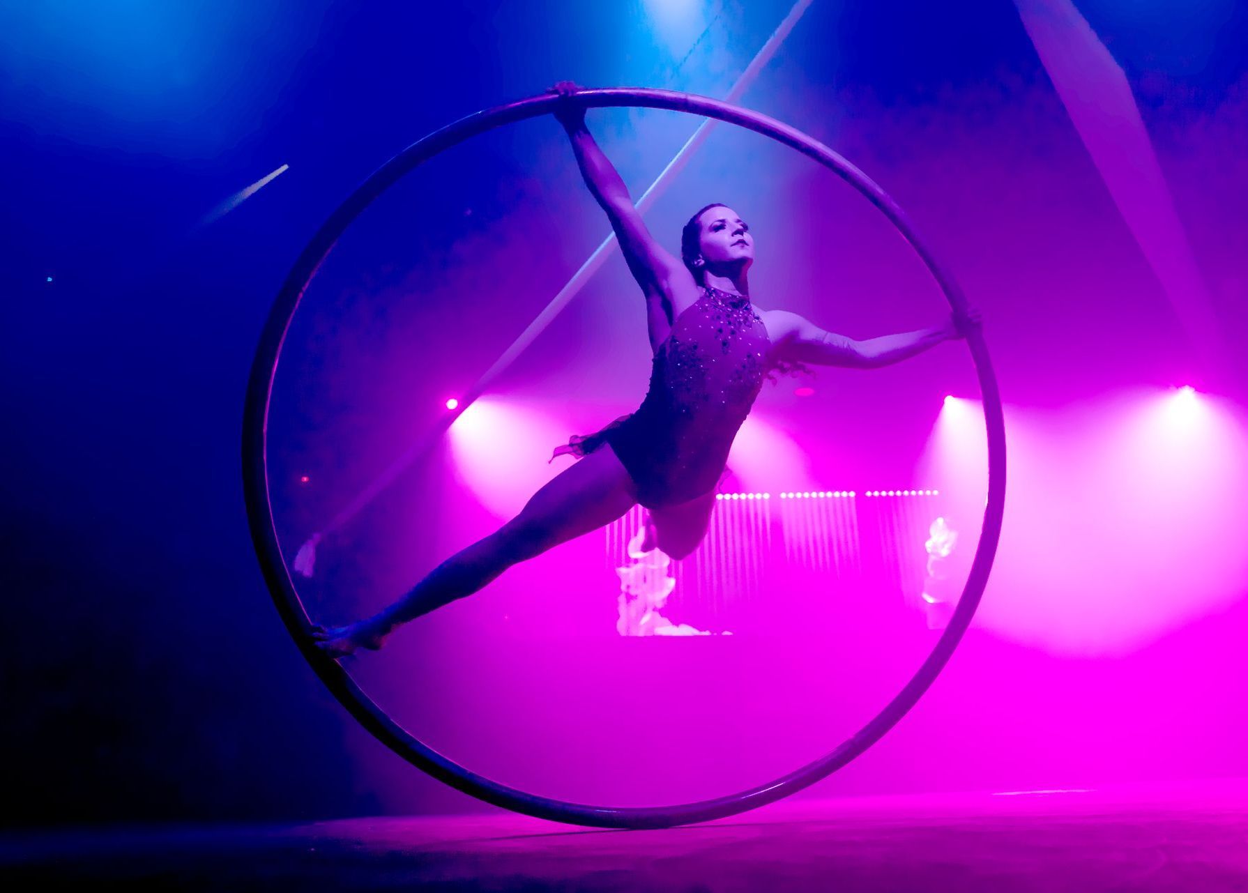 A woman is doing a trick in a hoop on a stage.