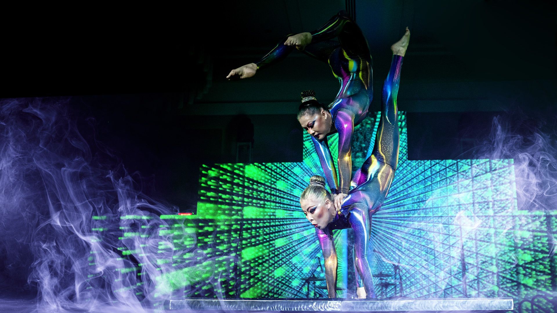 two women are doing ground acrobatics on a stage.