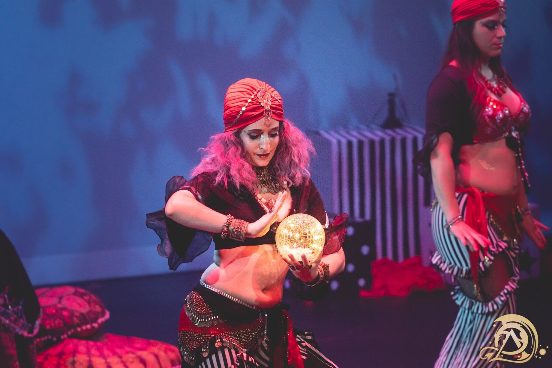 Two women are dancing on a stage and one is holding a glass ball.