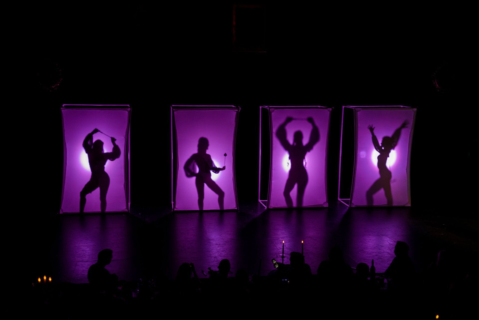 A group of people are performing on a stage with purple lights behind them.