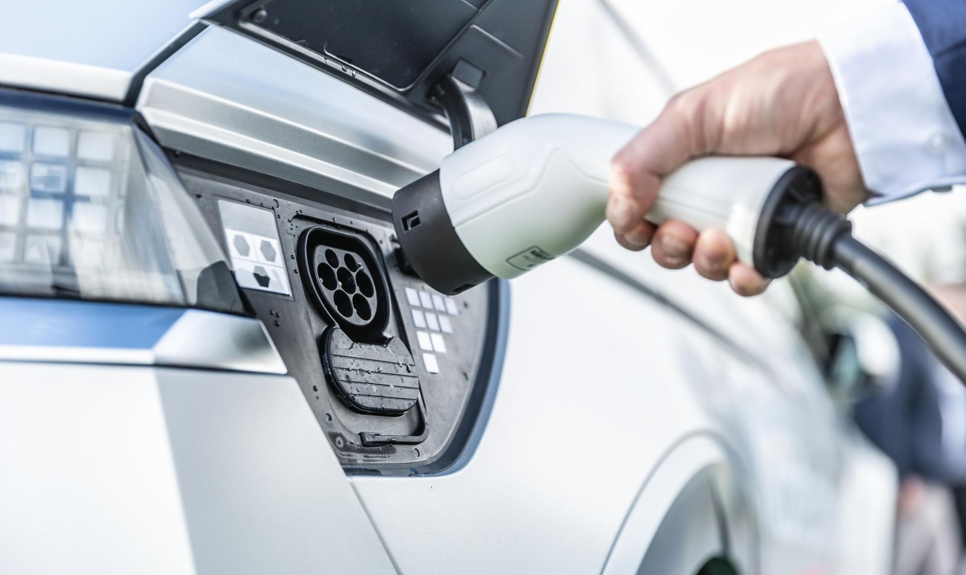 Hand Plugging an Electric Vehicle Charger Into a White Car's Charging Port  — Firefly Connections In Mayfield West, NSW