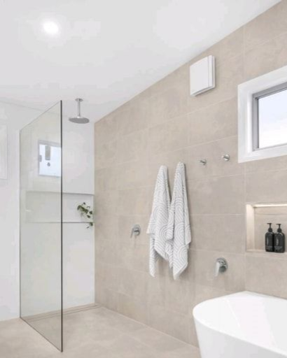 Modern bathroom with beige tiles, glass shower, and white freestanding tub — Firefly Connections In Teralba, NSW