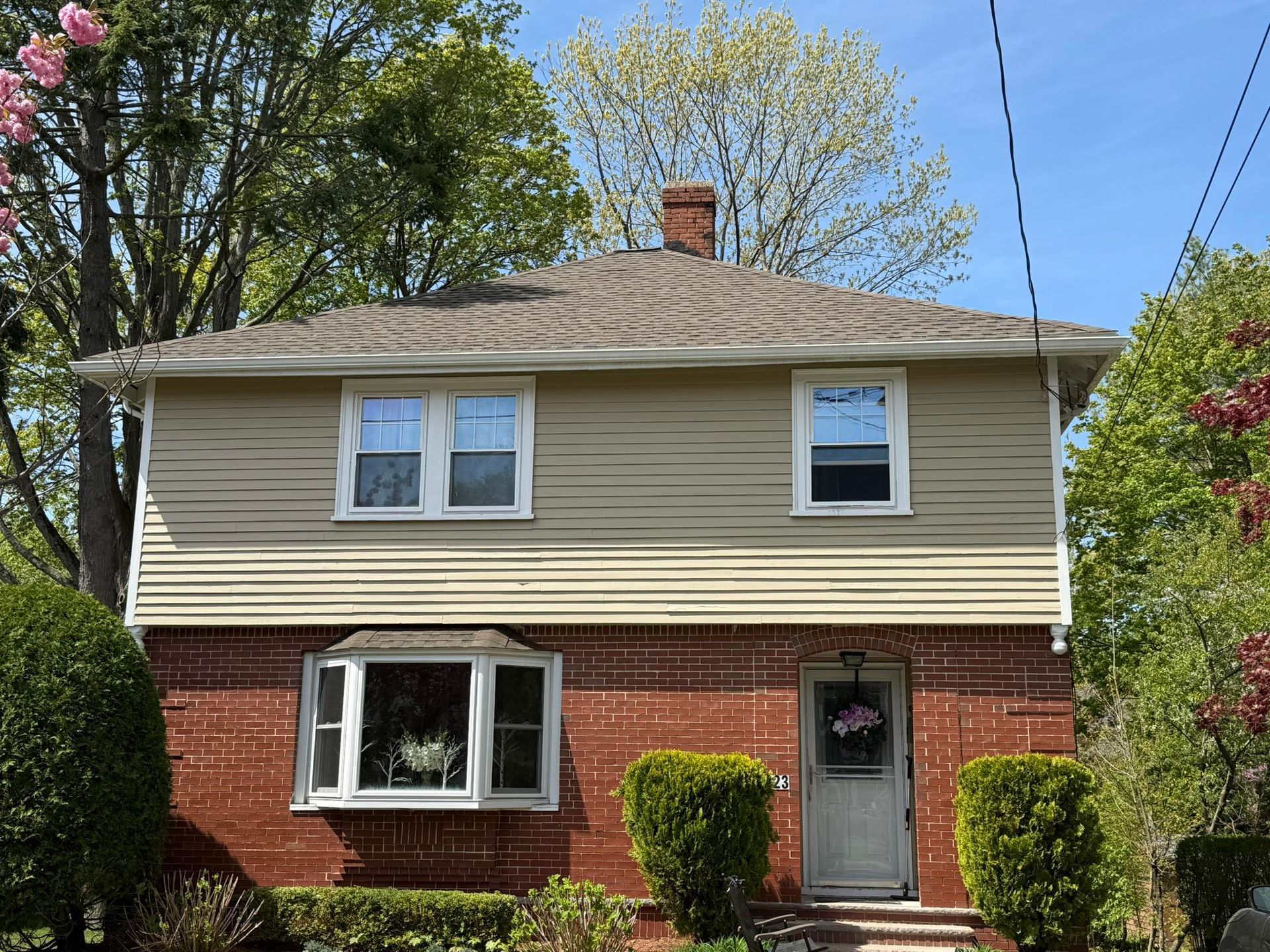 A brick house with a tan siding and a chimney