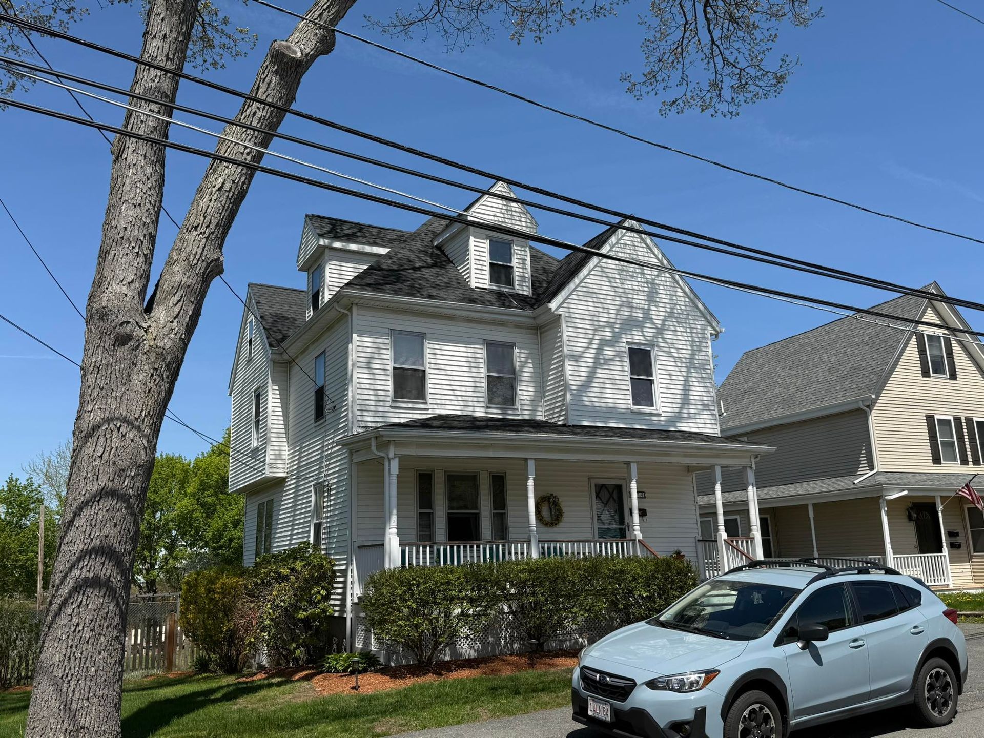 A car is parked in front of a large white house.