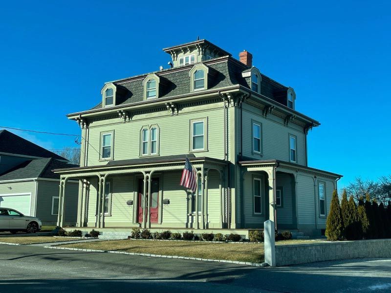 A large house with a porch and an american flag in front of it