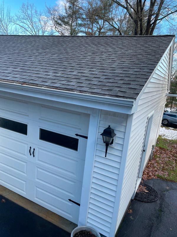 A white garage with a black roof and a white door.
