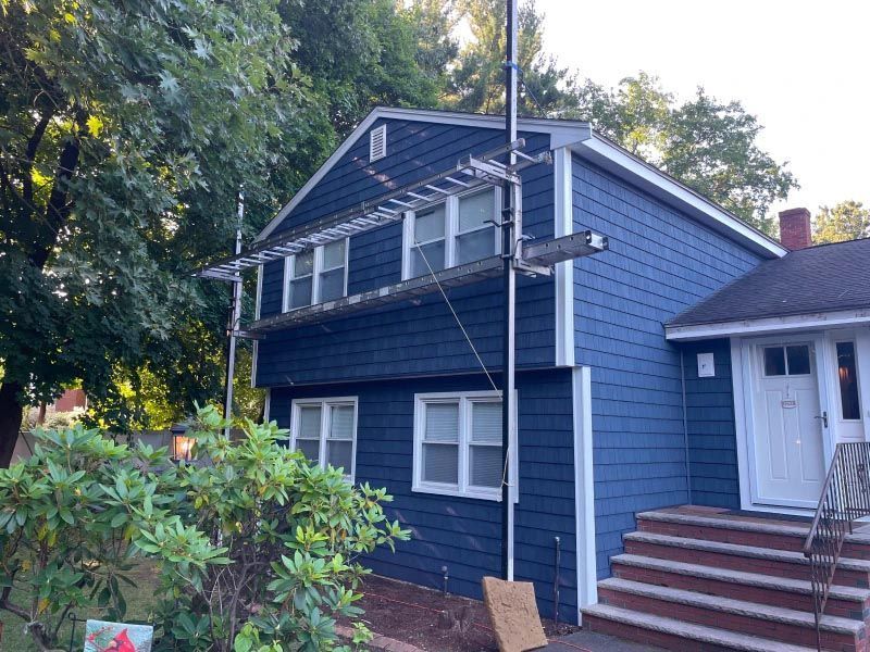 A blue house with a ladder attached to it is being painted.