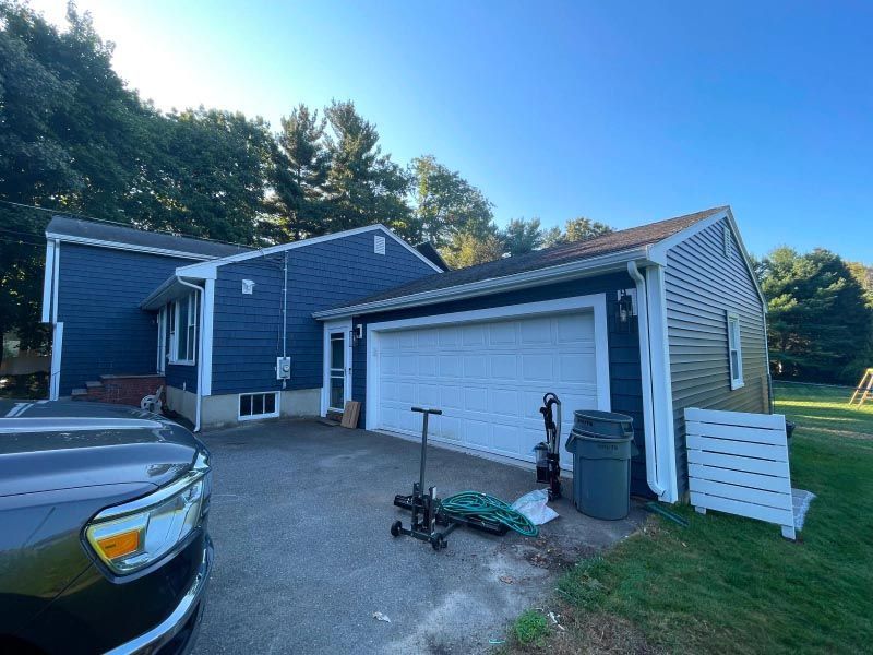 A truck is parked in front of a blue house with a white garage door.