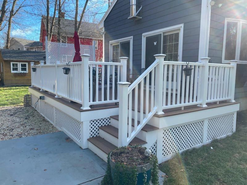 A deck with stairs and a white railing on the side of a house.