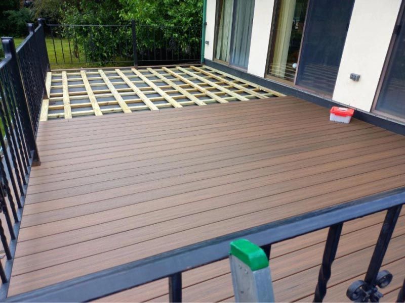 A wooden deck is being built in front of a house