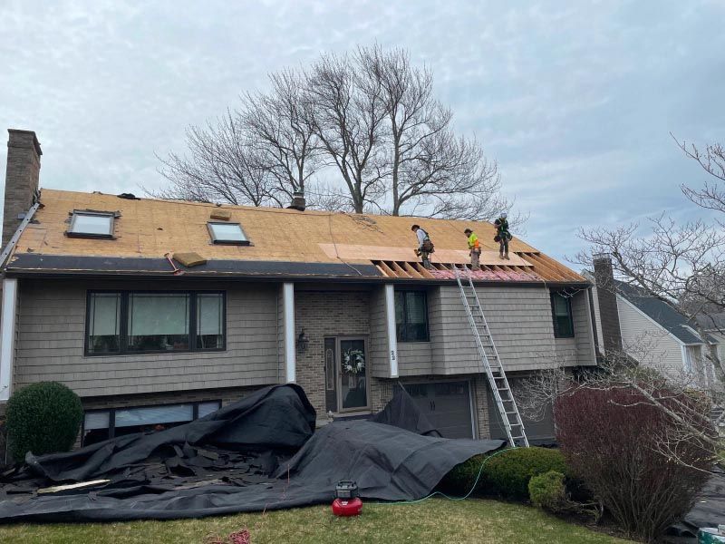 A group of people are working on the roof of a house.