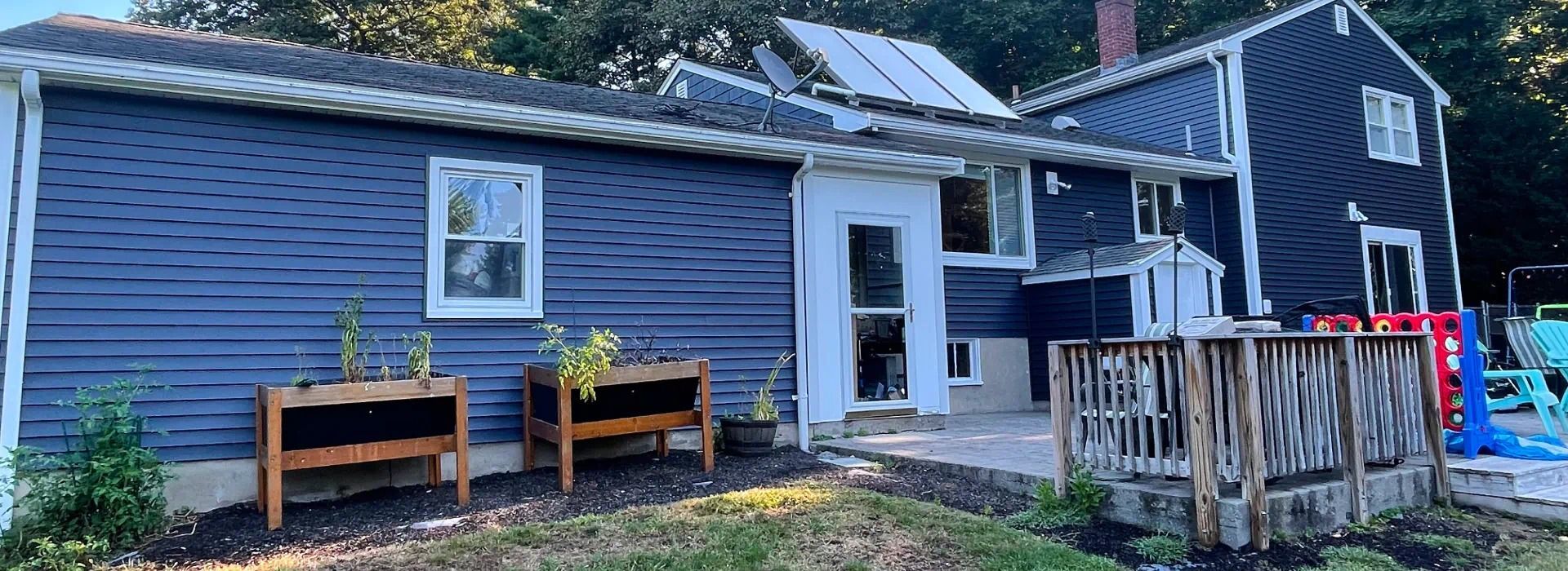 A large blue house with a deck and planters in front of it.