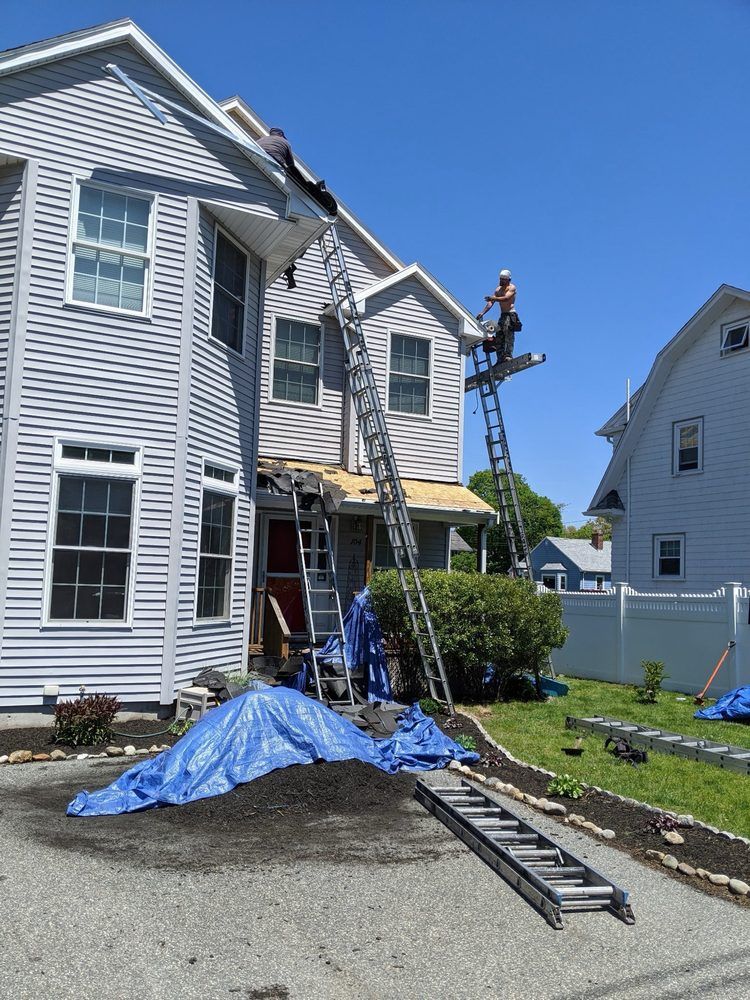 A man on a ladder is working on the roof of a house