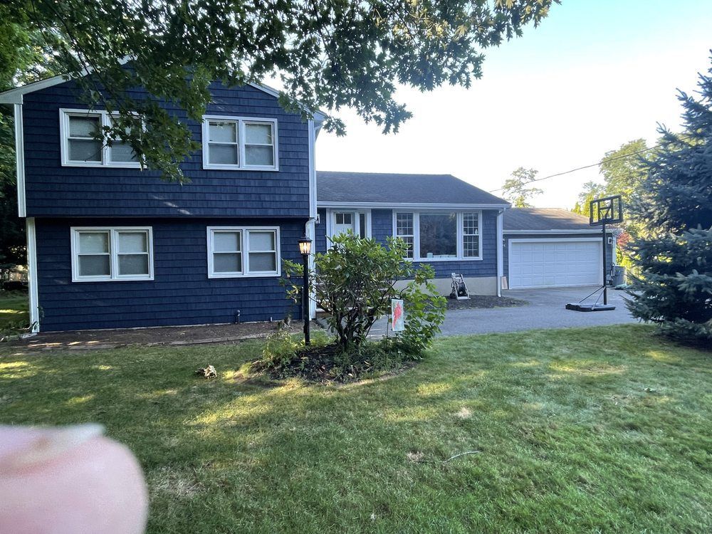 A person is pointing at a blue house with a white garage door.