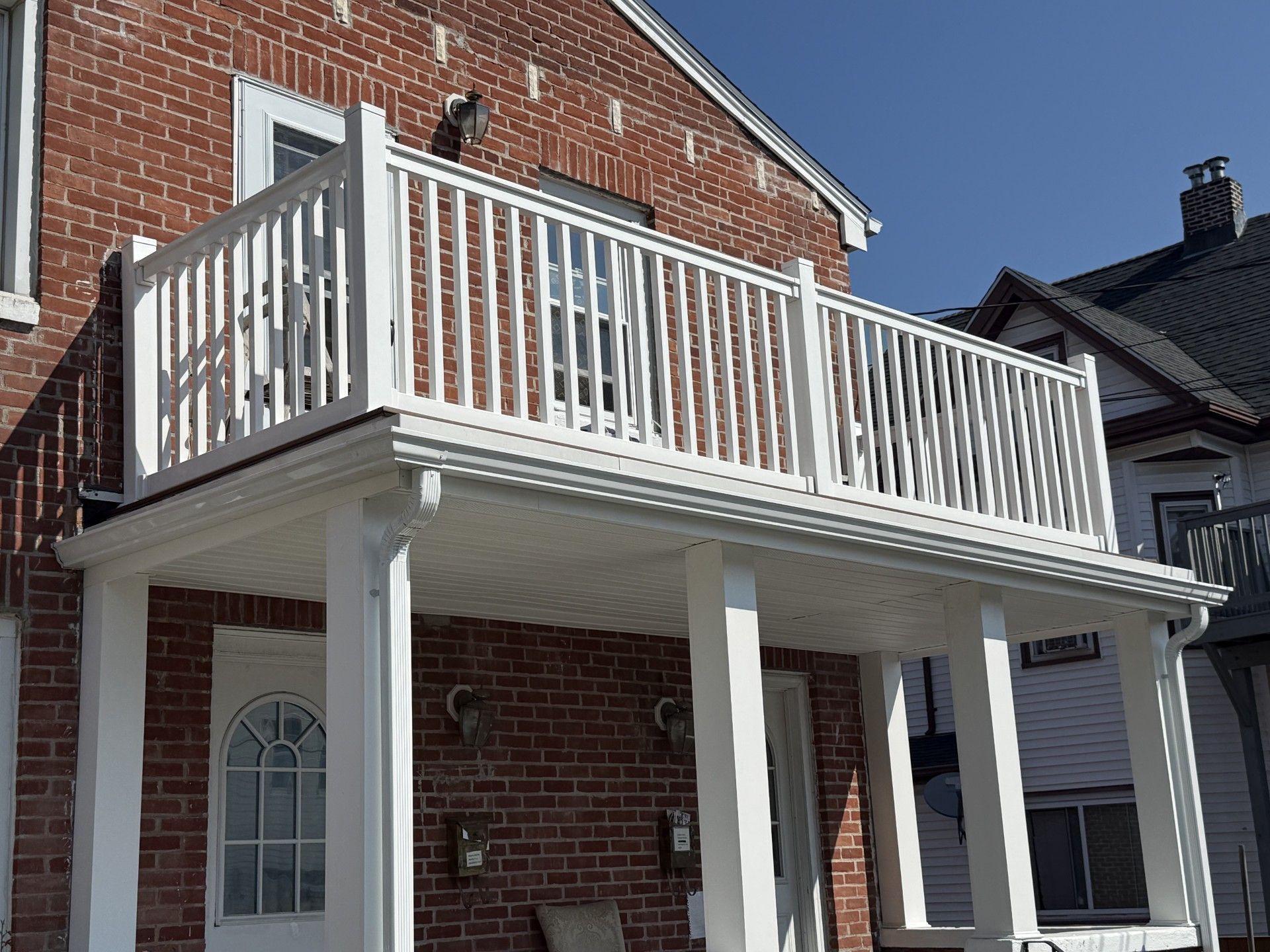 A brick house with a white porch and railing